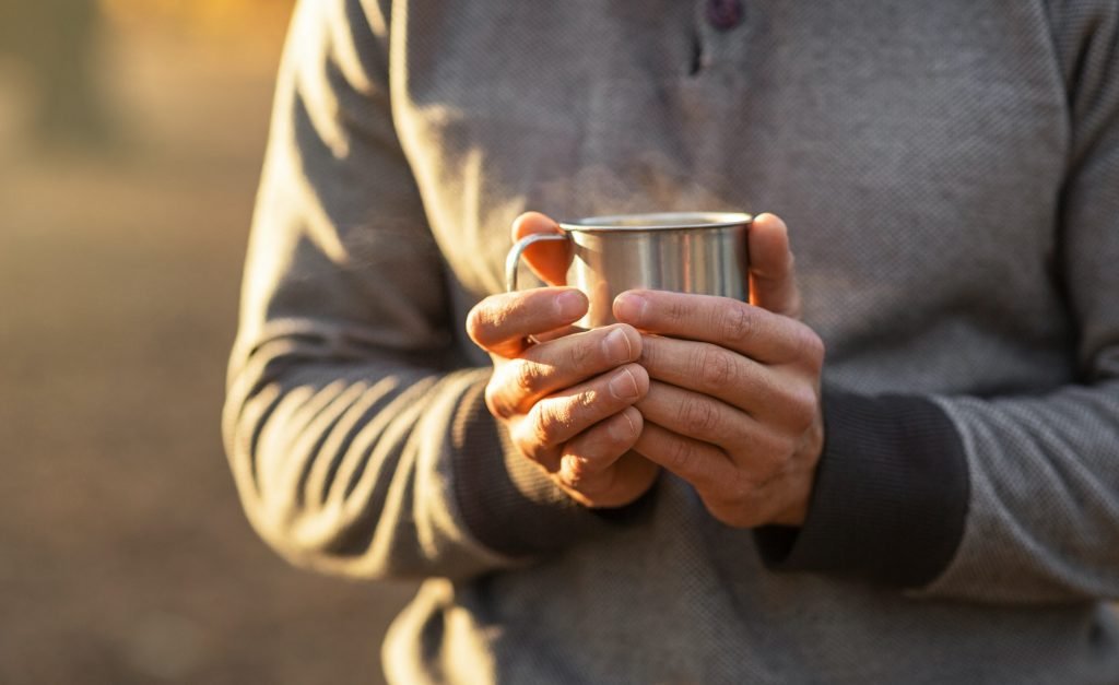 Male hands holding warm cup of tea or coffee