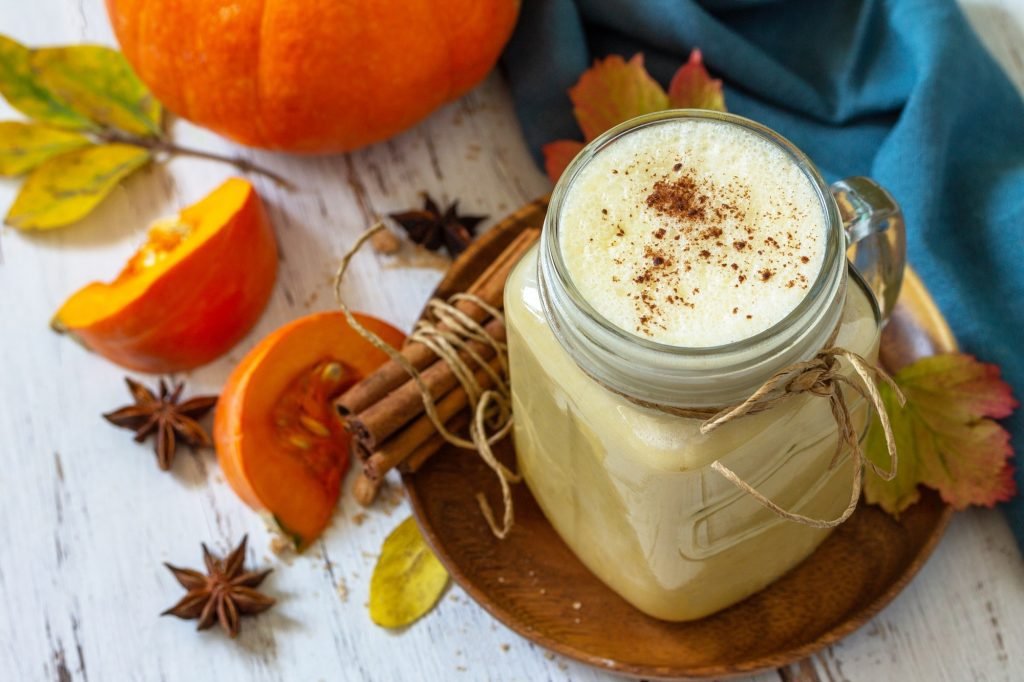 Autumn drink. Pumpkin spiced latte or coffee in glass on a rustic wooden table.