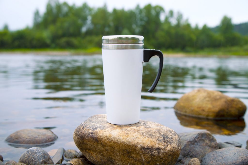 Placeit – White travel mug mockup with stony river bottom