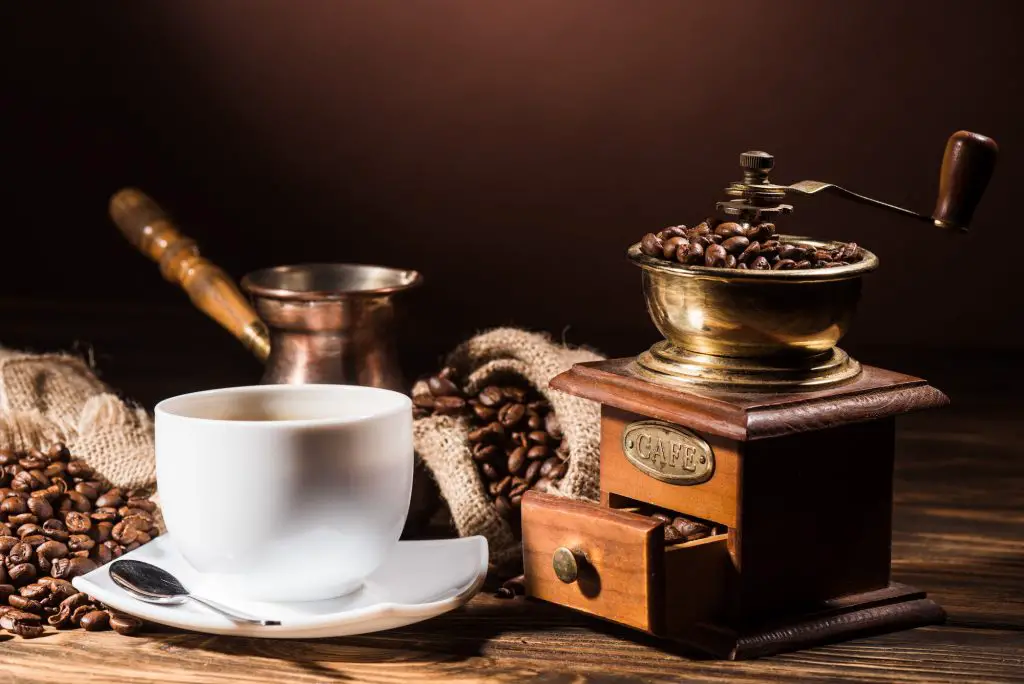 coffee cup with vintage cezve and coffee grinder on rustic wooden table