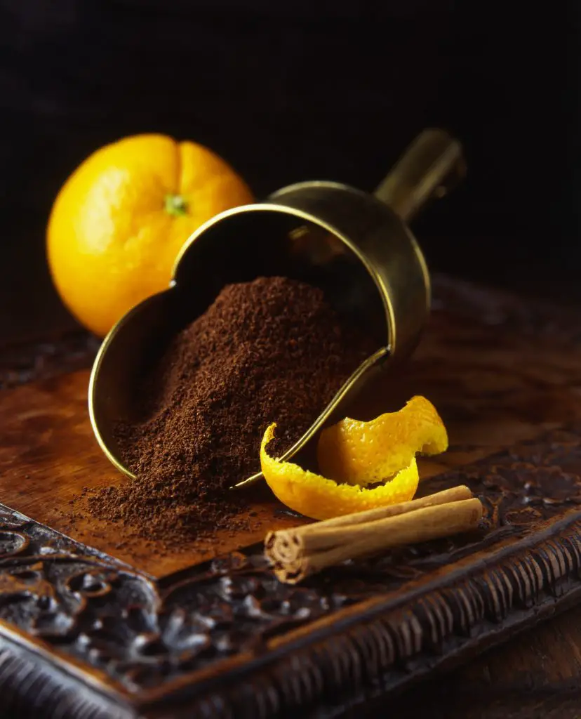 Fresh oranges and peels with cinnamon stick and freshly ground coffee in vintage scoop