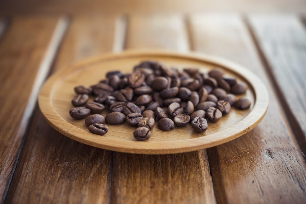 Closeup image of coffee beans on wooden saucer on the table