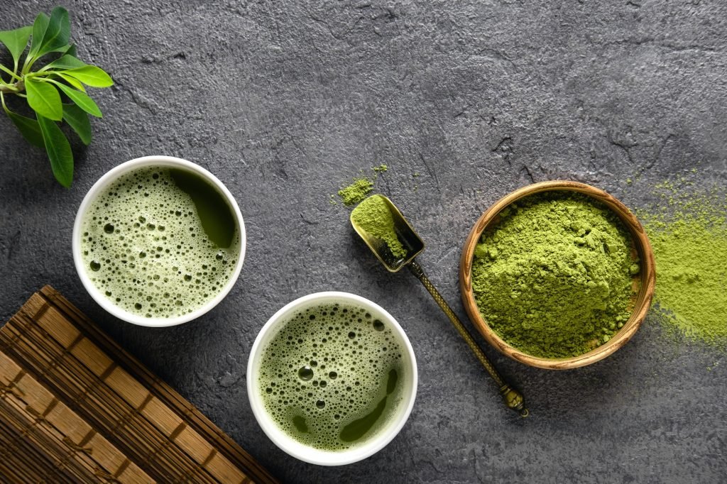 Matcha tea powder and tea accessories on dark background.