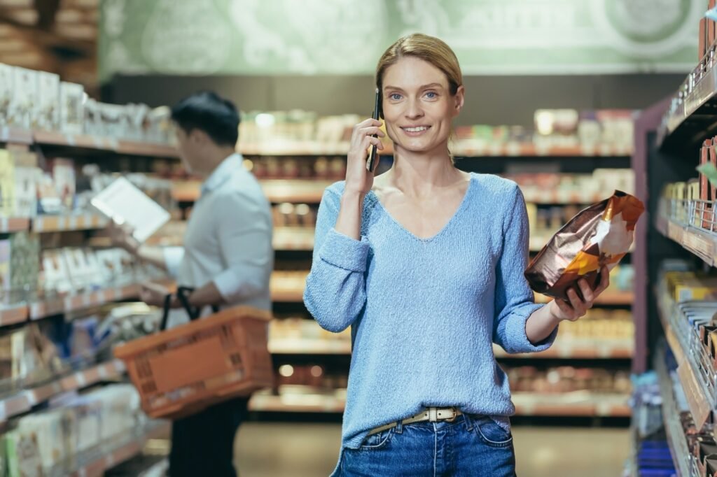 A woman in a supermarket and talking on the phone, consulting, holding a pack of coffee in her hand