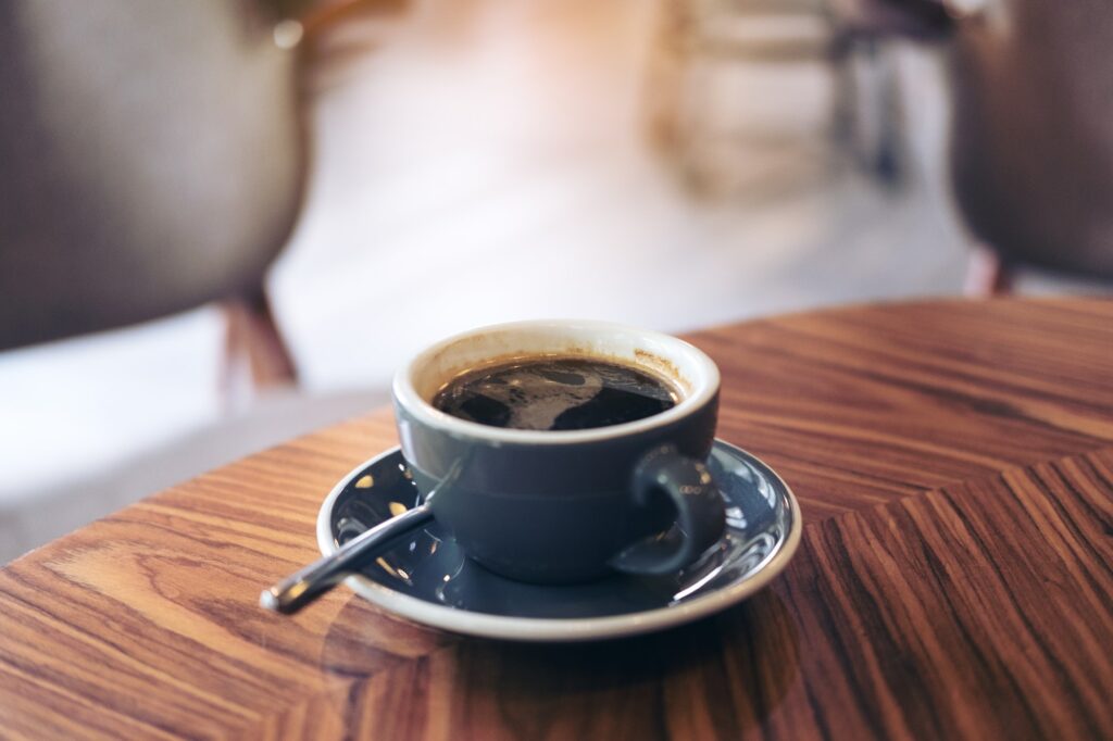 Closeup image of hot Americano coffee cup on vintage wooden table in cafe