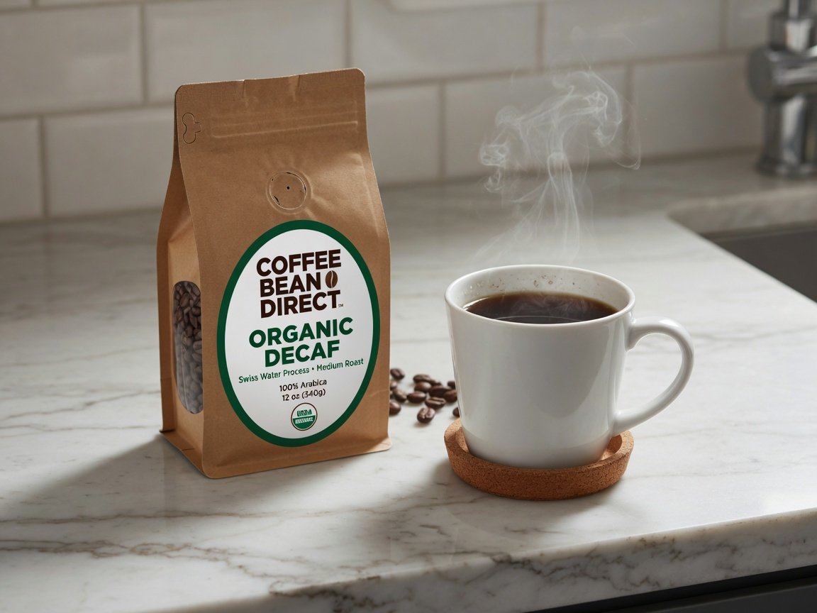 A bag of Coffee Bean Direct organic decaf coffee beside a steaming white ceramic mug on a clean marble kitchen counter